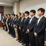 주주총회 입장 장면에서 사람들이 줄을 서서 기다리고 있음