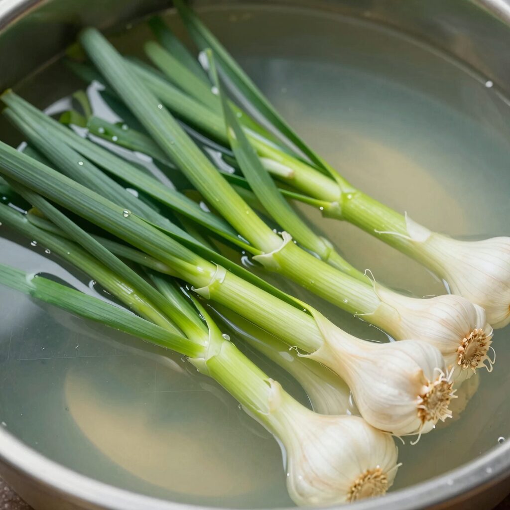 끓는 소금물에 마늘쫑을 데치는 과정으로 아삭한 식감과 선명한 초록색을 유지하는 방법을 보여줍니다