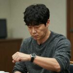 구교환이 연기한 황동만이 감정워치를 보며 복잡한 표정을 짓고 있는 장면