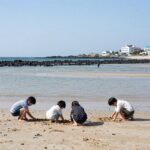 제주 해수욕장 물때 확인하고 아이와 안전하게 물놀이 제주 협재해수욕장 간조 때 얕은 바닷물과 아이들이 모래놀이하는 모습